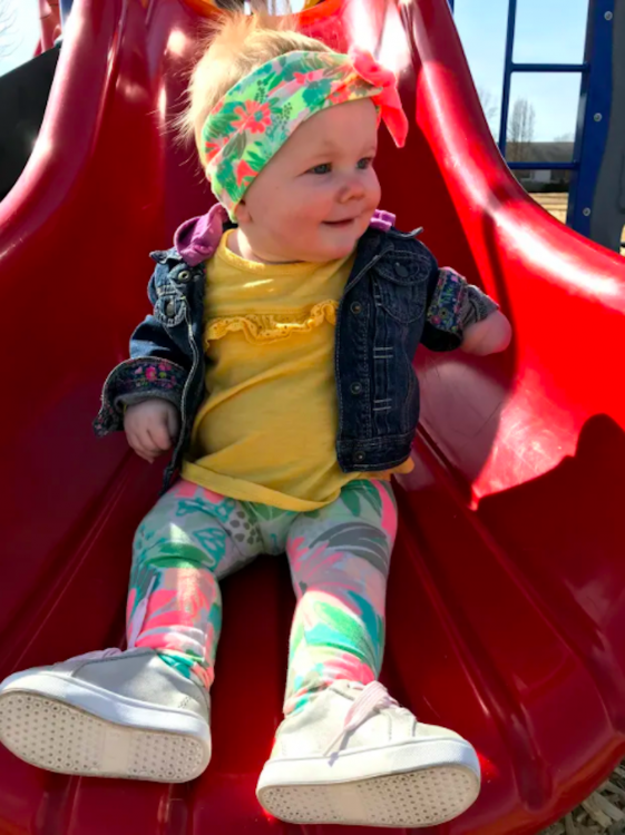 Adorable little girl going down a slide, her right hand is missing