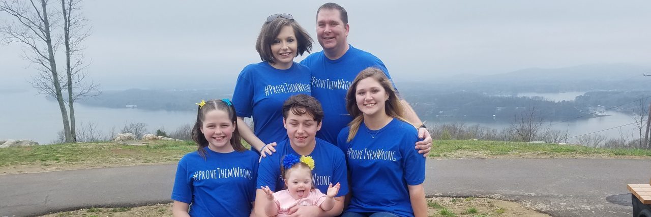 Family of 6, baby has Down syndrome, they all wear a blue shirt that says "provethemwrong