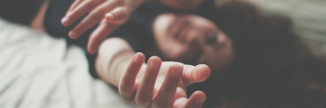Why My Therapist ‘Gave Up’ on Me and My Anxiety Recovery photo of woman lying in bed reaching out to camera
