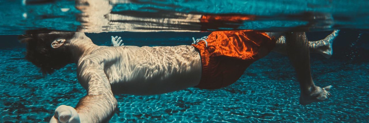 man floating in clear blue water