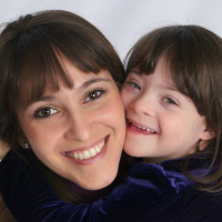 Mother hugging daughter with Down syndrome, face close up.