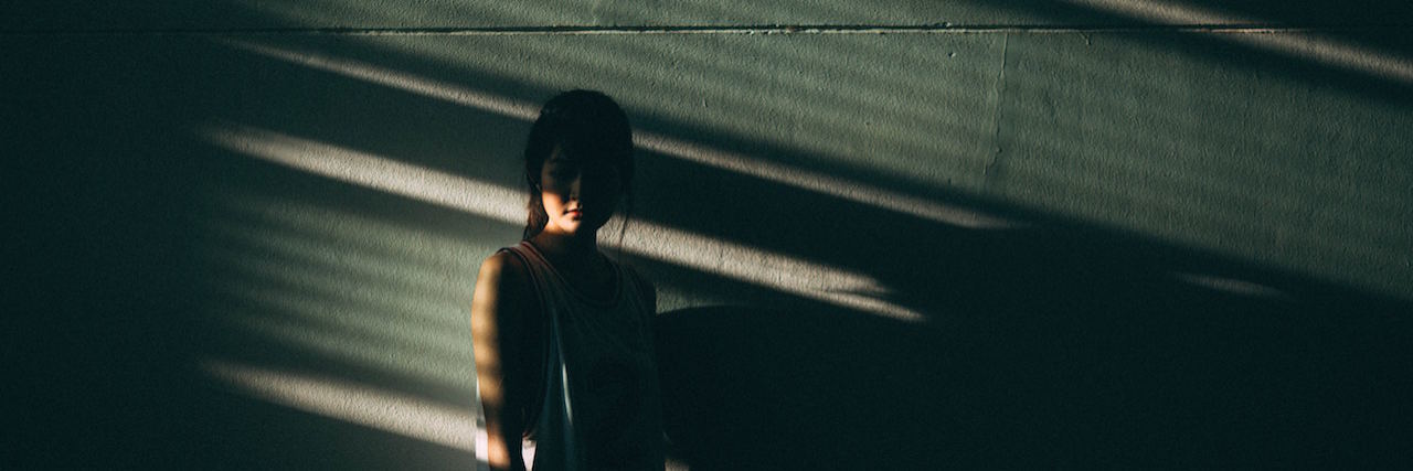 A woman standing in shadows