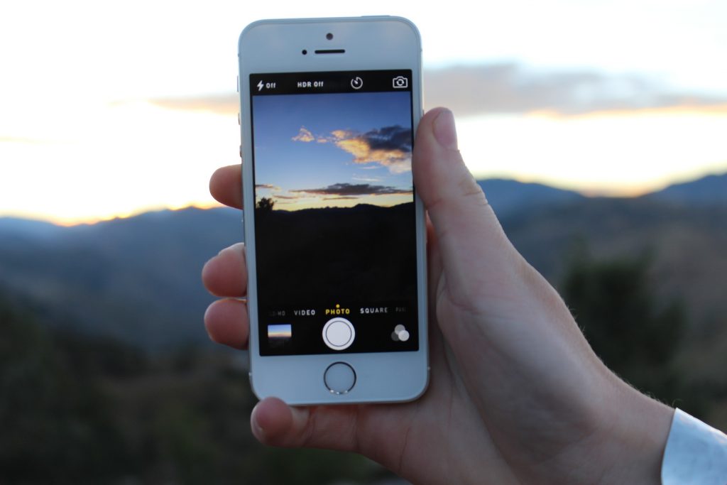 woman taking a picture of a sunset with her iphone