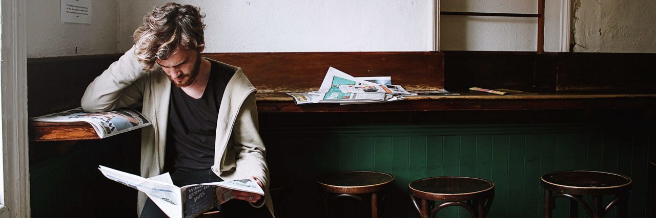 How to Manage Anxiety When School Shootings Happen young man reading newspaper looking worried