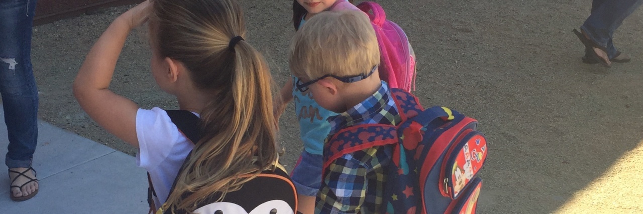 Including My Son With Down Syndrome Benefits Everyone in the Classroom Three children holding hands walking into school, in the middle is a little boy with Down syndrome