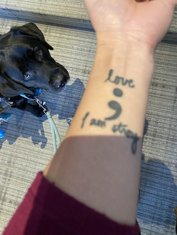 Tattoo on a person's forearm with a semicolon and the words "love" and "I am strong"