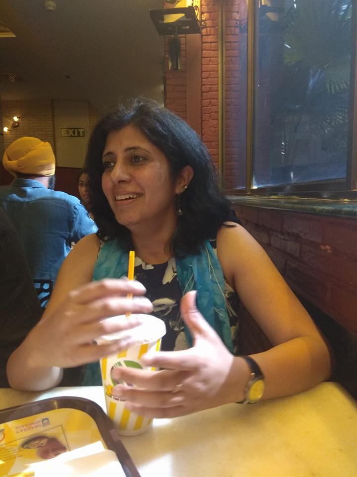 woman sitting in a restaurant with a drink in front of her