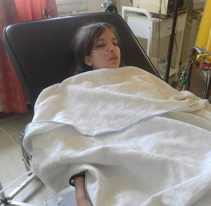 woman lying in a hospital bed covered with a blanket