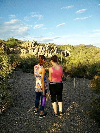 two girls hiking with one carrying a large water bottle
