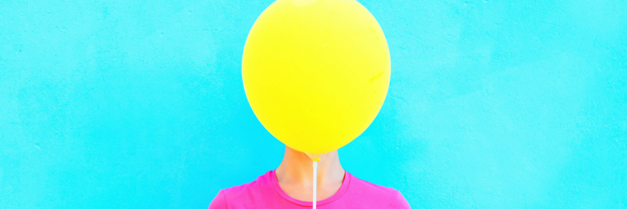 16 Ways People Hide the Fact That They're Depressed woman with balloon in front of her face