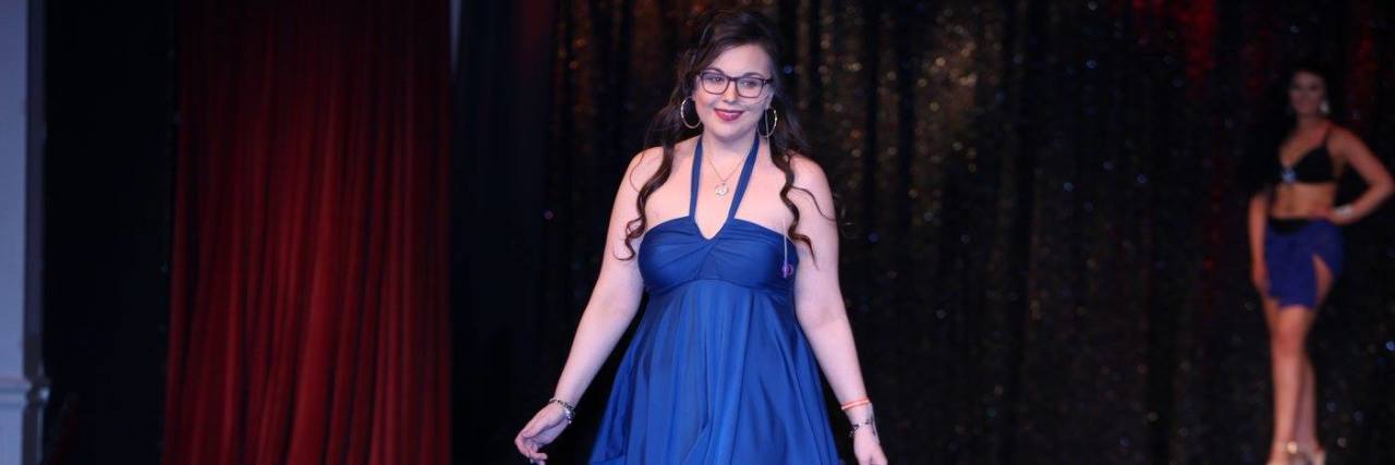 I'm a Chronically Ill Beauty Queen A photo of the writer walking down the runway in a beautiful knee-length blue dress.