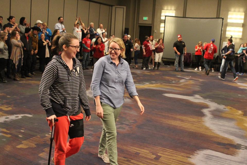 two women walking together and smiling at an indoor event