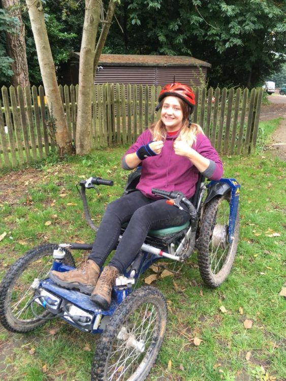young woman giving thumbs up in wheelchair outdoors