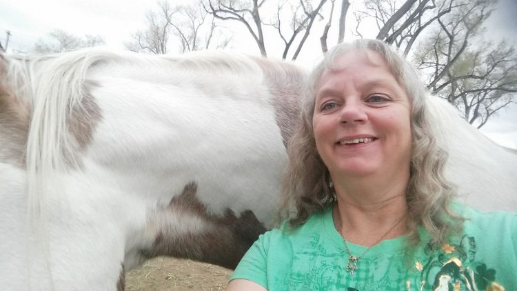 woman standing with white and brown horse