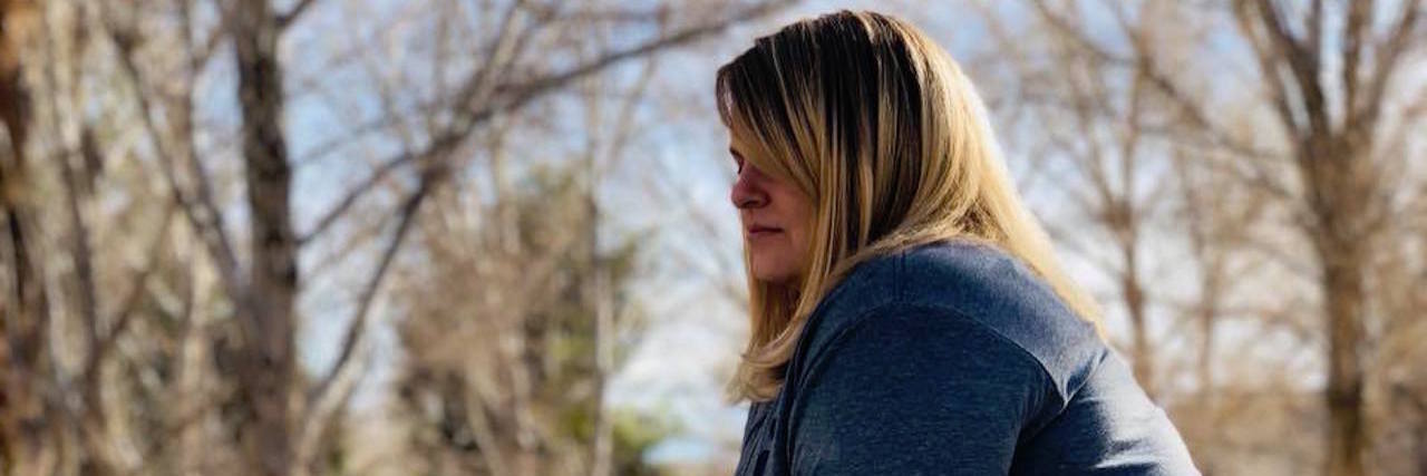 Endometriosis Doesn't Define Me the author leaning on a wall outside with trees in the background