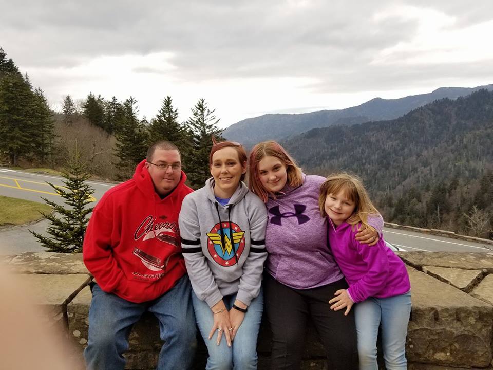 woman with her husband and two daughters in front of mountains