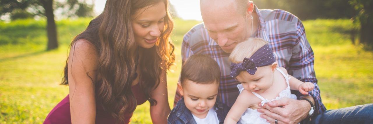 Synapse Sitters Helps Parents of Disabled Kids Find Babysitters Family of four reading a book outdoors