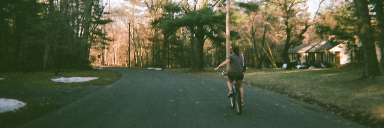 The Toughest 'Pill' for Me to Swallow When It Came to My Illness A picture of the writer riding a bike down a street.