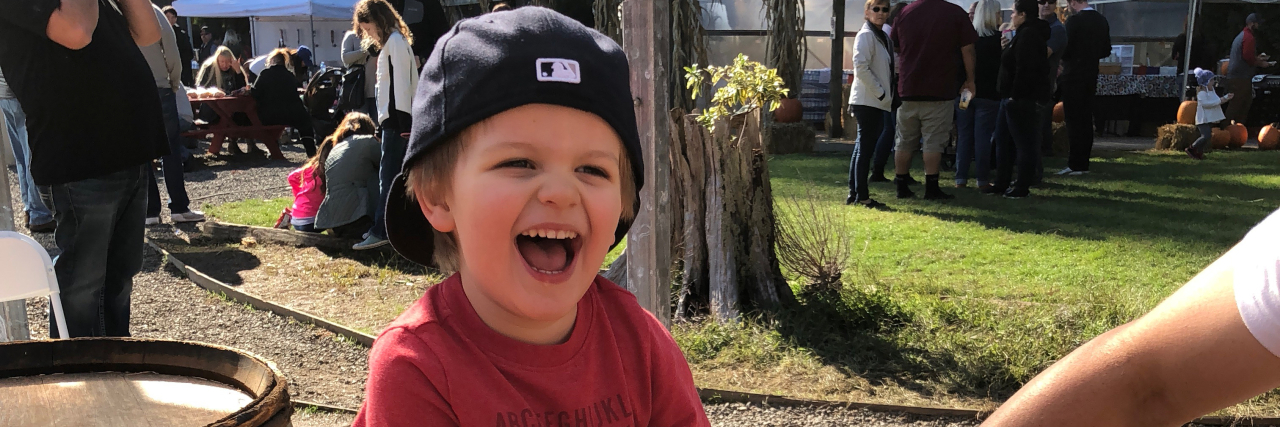 My Son on the Autism Spectrum Is Wired Wonderfully Toddler sitting on hay bale, laughing