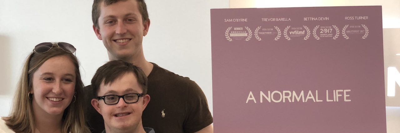 Why I Made a 'Normal' Movie About Down Syndrome Alex with his brother and mom standing next to movie poster for "A Normal Life."