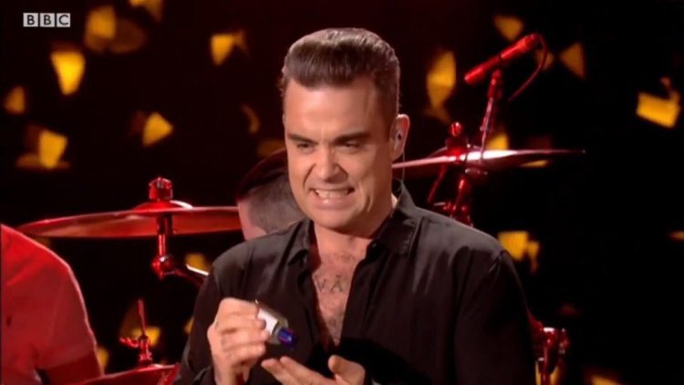 robbie williams using hand sanitizer and making a face