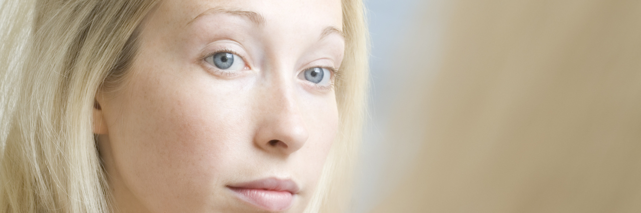 The 'Happiness Paradox' of Dealing With Infertility Serious woman peering into mirror looking at her reflection and brushing hair with hairbrush