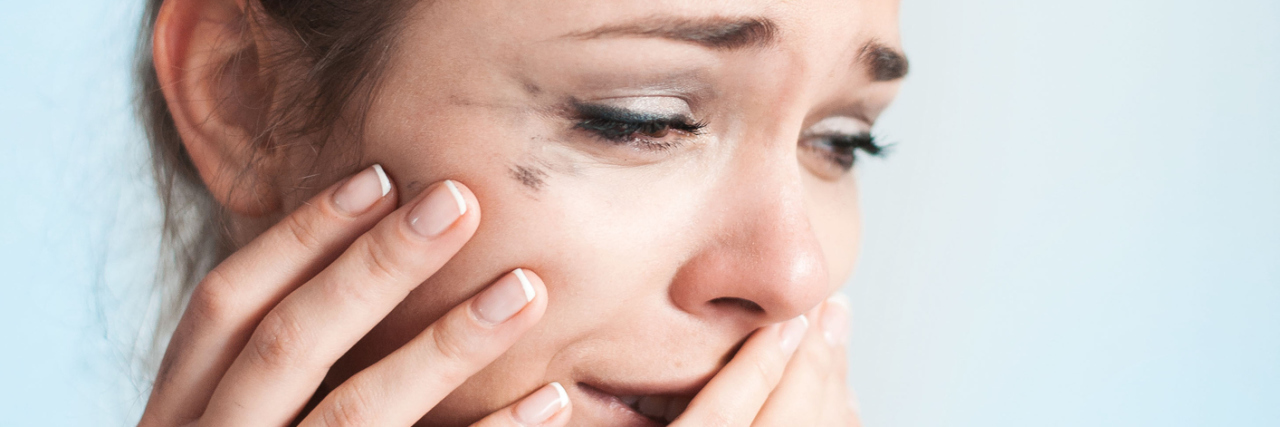 A woman crying with mascara running down her face.