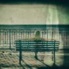 Blond woman sitting on a bench and looking at sea.