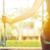 young woman sitting on swings alone missing someone