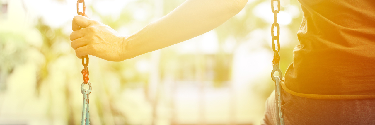 Dating and Feeling Needy as a Person With Depression young woman sitting on swings alone missing someone