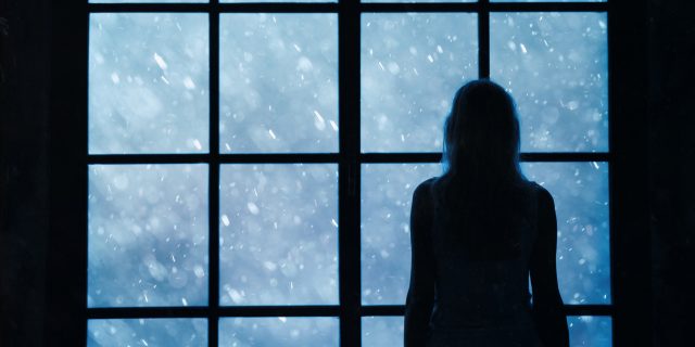 Lonely woman standing and looking out a window