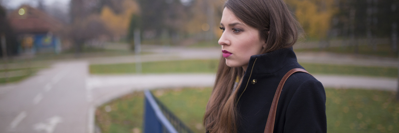 Deciding Not to Have Children So I Don't Pass Down My Illnesses woman standing outside in a black coat looking away
