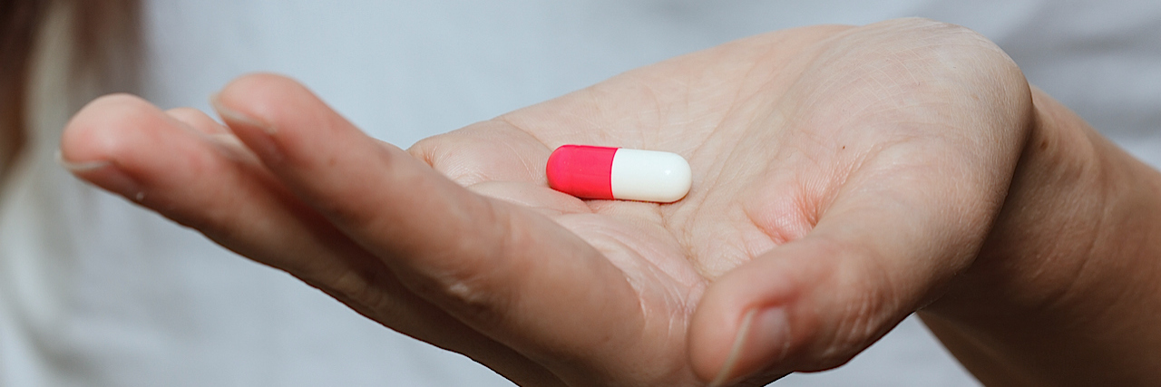 A woman holding a capsule pill