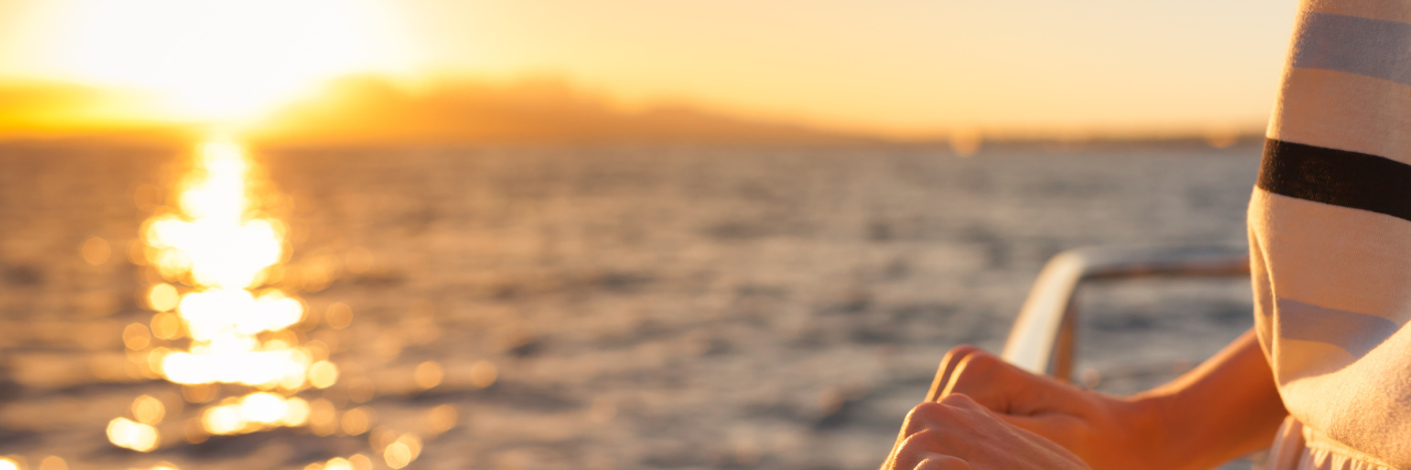 What It's Like Being Single With a Seizure Disorder, Chronic Illnesses woman's hands holding the railing of a boat with the ocean in the background at sunset