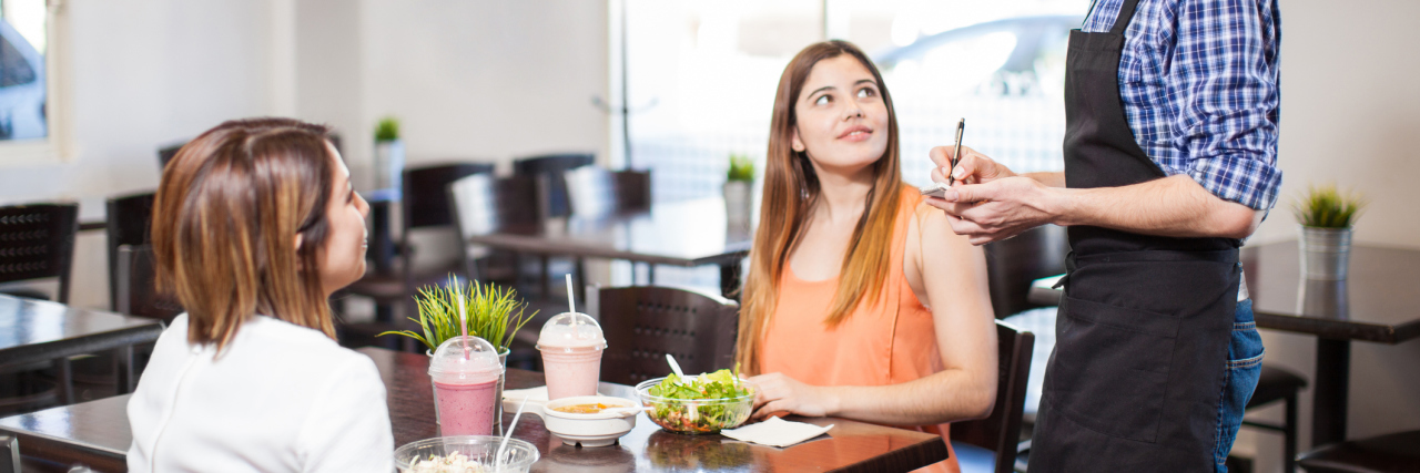 Ordering a Kids' Meal or Small Portion at a Restaurant Due to Illness two women ordering food from a waiter at a restaurant