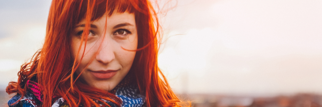 Feeling Happy and Relieved to Be Diagnosed With Fibromyalgia woman standing outside with red hair blowing in the wind