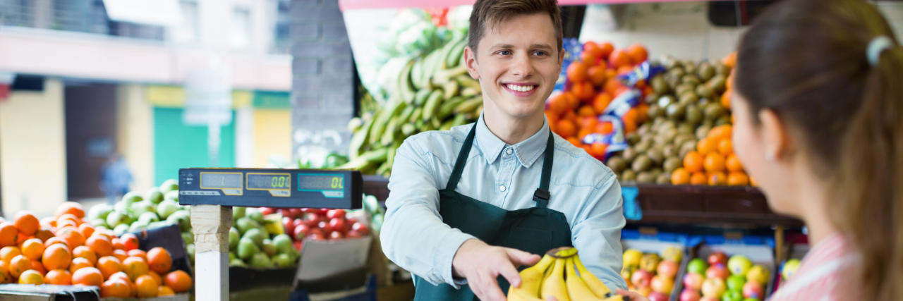 Finding Autism Acceptance in the Workplace Grocery employee assisting customer with bananas.