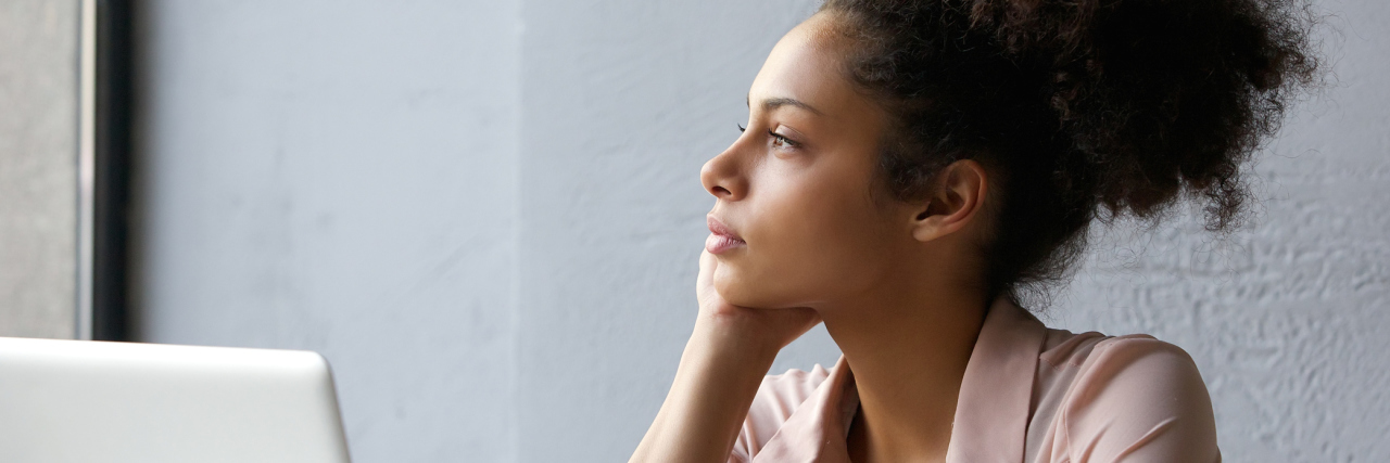 Thinking About Your Dream Job When Living With Chronic Illness woman at work on her computer but staring off into the distance
