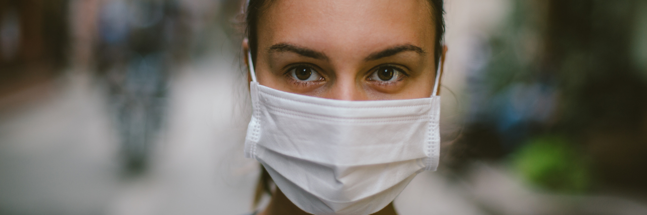 Primary Immune Deficiency Awareness Month Questions and Answers Young woman wearing face mask in the street.