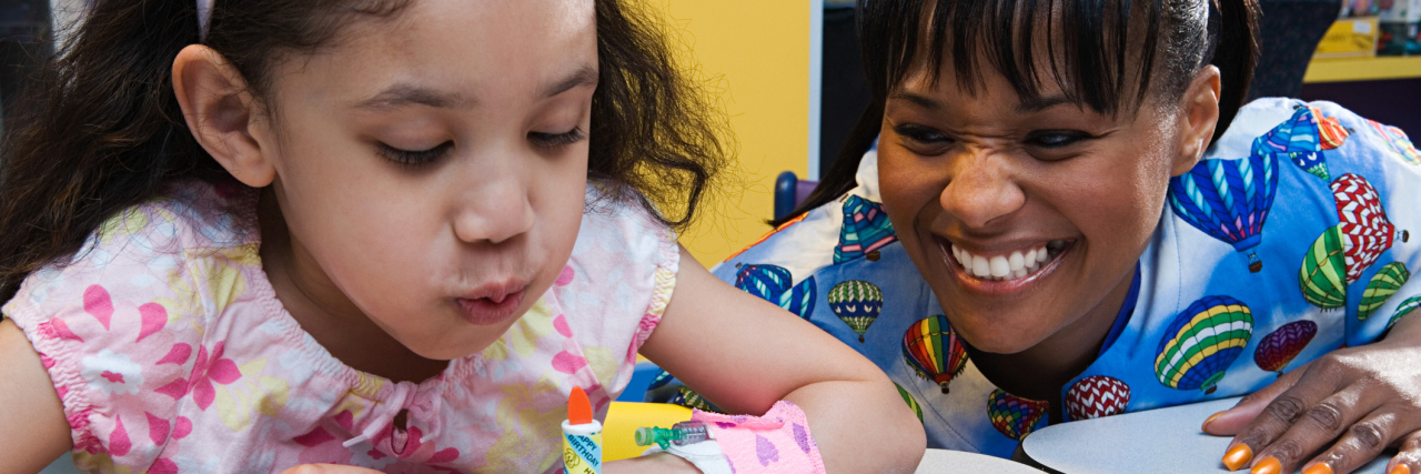 A woman playing with a child with an IV port in her arm.