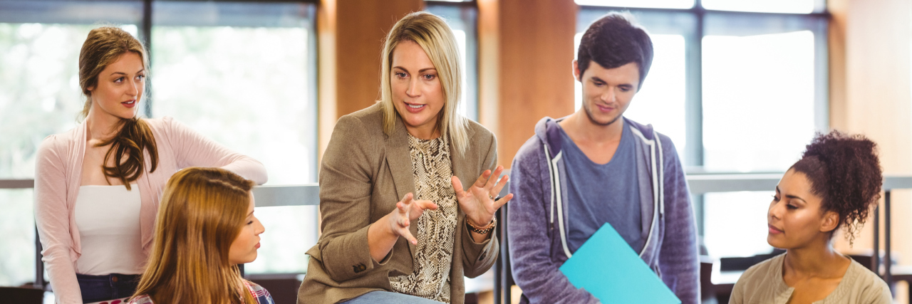 A teacher talking to a group of college students.