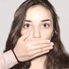 Portrait of young girl covering her mouth.