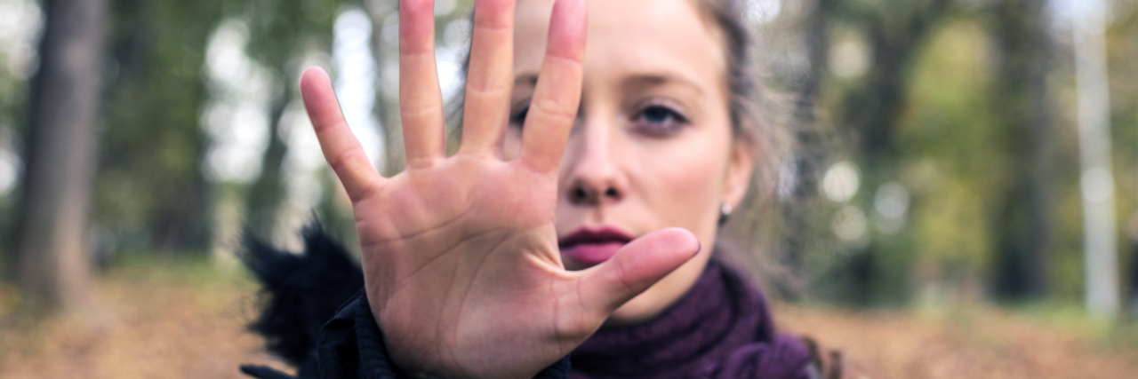 Woman in woods holding hand out in stop gesture