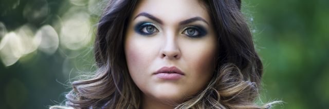 A plus size woman looking into the camera with a serious expression.