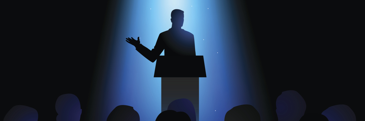 Silhouette of a man giving a speech on stage.