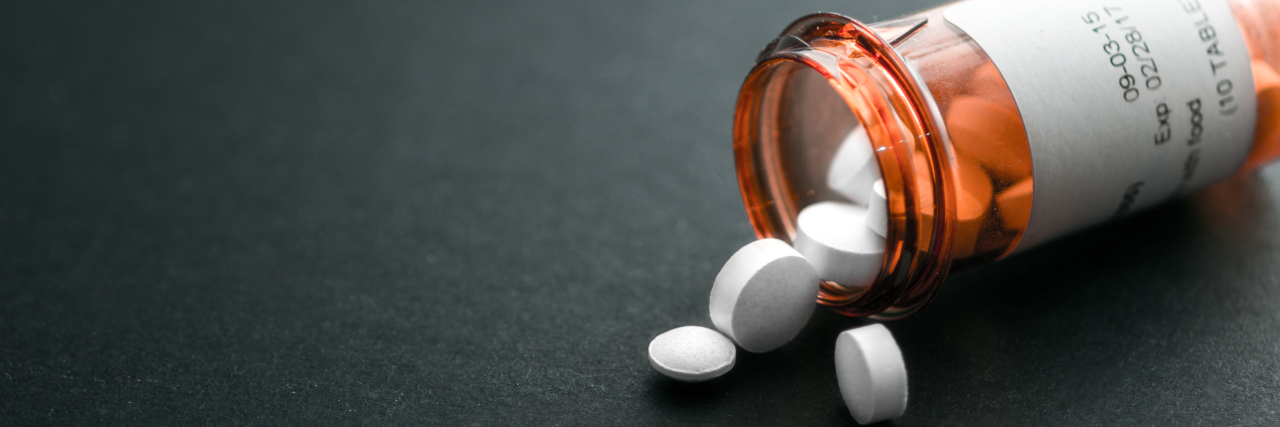 The High Cost of Epilepsy Medication Pill bottle spilling out pills onto a black surface.