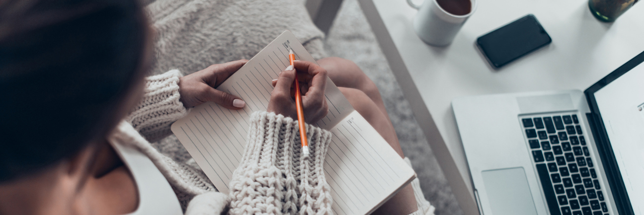 What to Do If You Have Chronic Illness and Are Bored at Home woman curled up on her couch writing in a journal