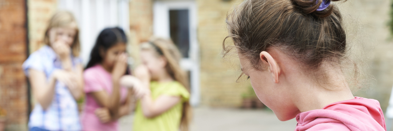 We Need Better Policies Against Bullying Students With Health Issues three girls whispering and pointing to one girl standing alone