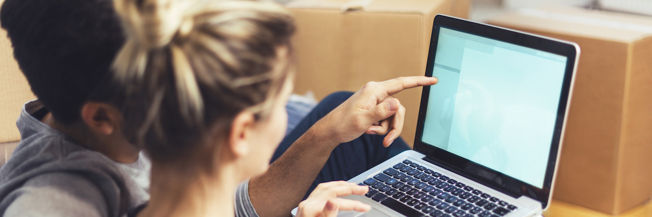 Net Neutrality Changes Weaken Efforts to Prevent Suicide Young couple sitting between boxes and using a laptop