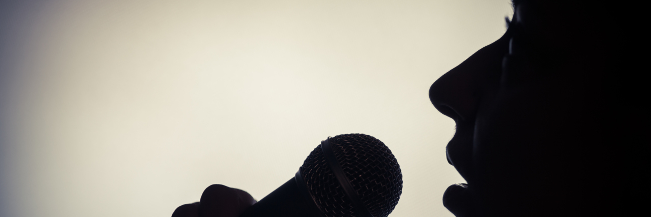 Silhouette of a woman singing with a microphone.